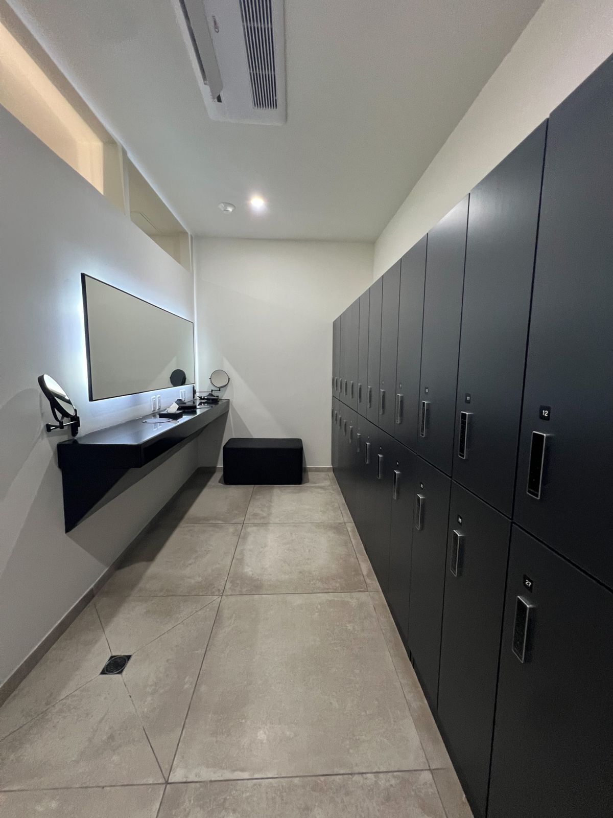 Changing room with lockers and a lit vanity mirror